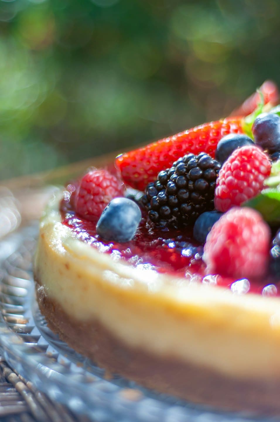 Tarta de queso con frutos rojos frescos en un plato de cristal.