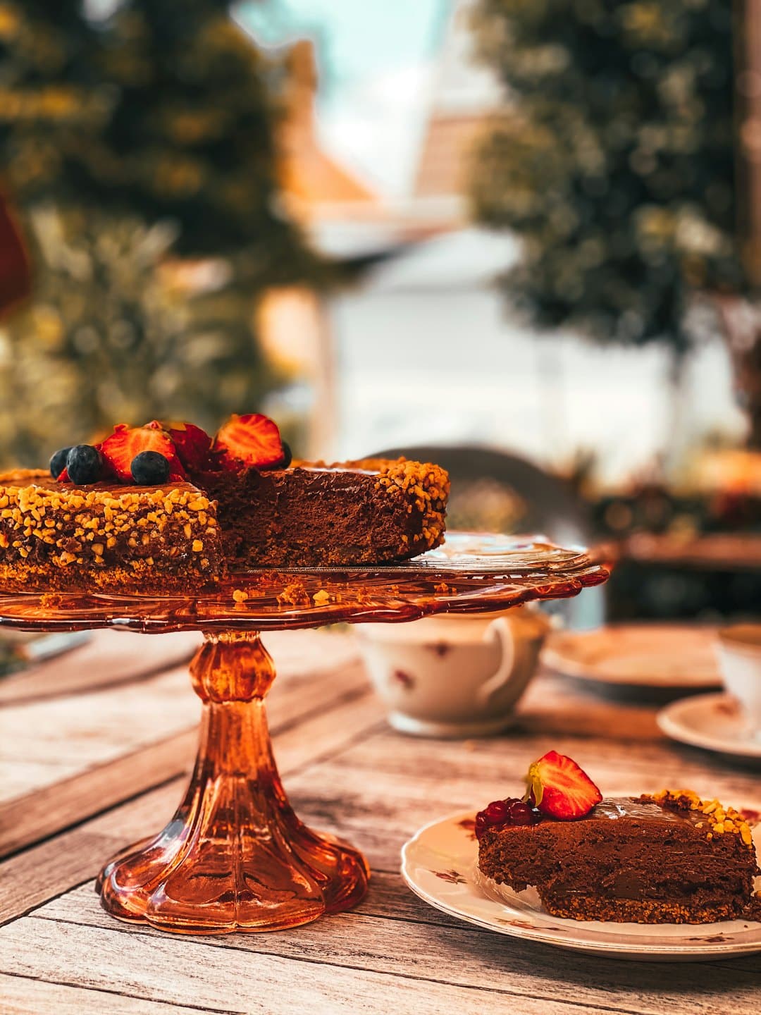 Pastel de chocolate con frutos rojos sobre un soporte de cristal.