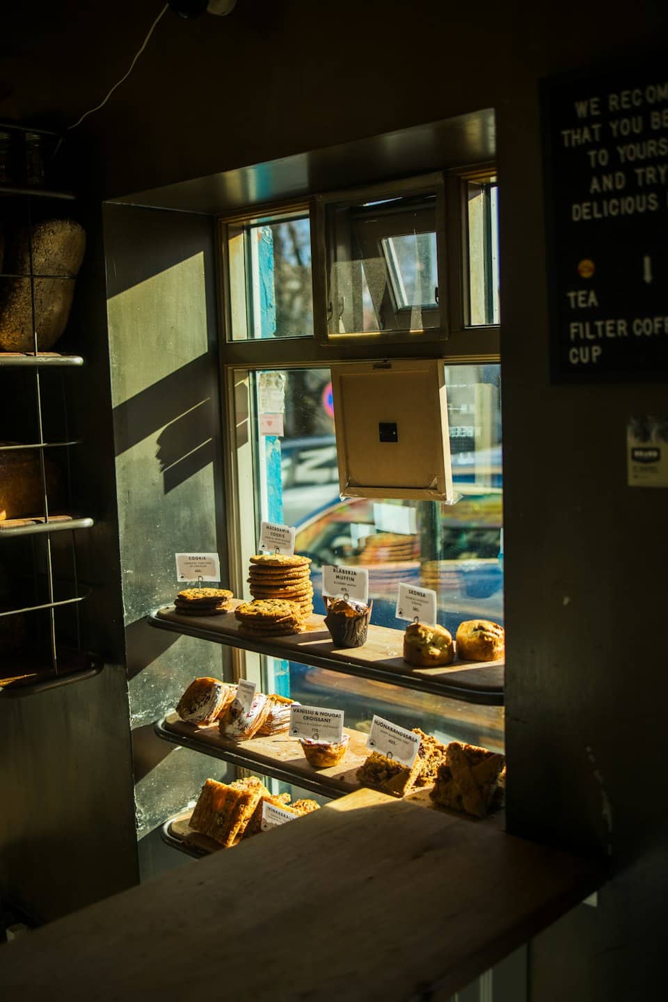Surtido de pasteles frescos expuestos en estantes de madera dentro de una panadería.