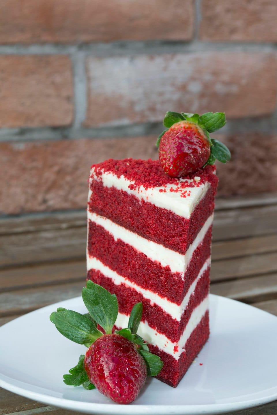 Una rebanada de pastel terciopelo rojo en capas, coronada con una fresa fresca.